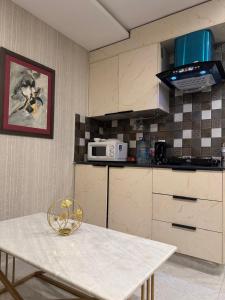 a kitchen with a white table and a microwave at Stayease in Lahore