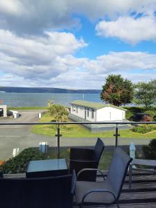 a balcony with chairs and a view of the water at Wild Thistle static Caravan in Kirkcolm