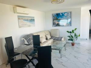 a living room with a couch and a glass table at Ferienhaus direkt am Strand mit Terrasse und Meerblick in Torrevieja in Punta Prima