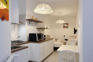 a kitchen with white cabinets and a microwave and a living room at La casa di Sally - Silenzioso Bilocale in centro in Trieste