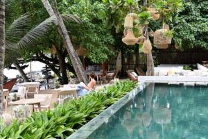 a woman sitting next to a pool at a resort at Petti Petti Beach Club- Mirissa in Mirissa