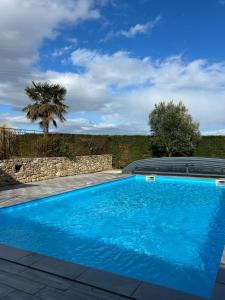 a blue swimming pool with a palm tree in the background at La Maison dans les Nuages in Sécheras