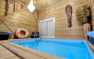 a house with a swimming pool and a wooden wall at Gîte des champs étoilés in Thuboeuf