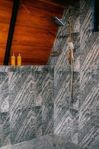a shower in a bathroom with a stone wall at Brilliant View Cottages in Ella