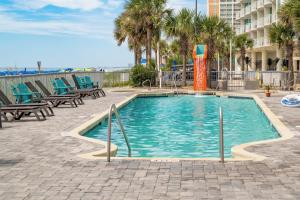 a swimming pool with blue chairs and palm trees at Modern Decor Stunning Ocean View Condo Sleeps 8 in Myrtle Beach