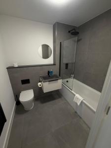 a bathroom with a toilet and a sink and a tub at Berkeley Square Apartments by StaySavvy Accommodation in Manchester +79 photos