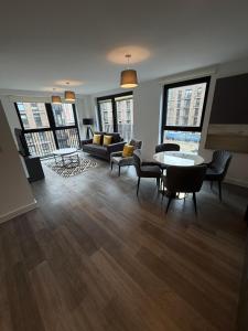 a living room with a couch and a table and chairs at Berkeley Square Apartments by StaySavvy Accommodation in Manchester