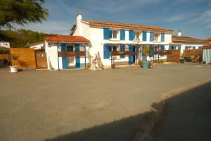 a white house with blue windows and a fence at La Norélie in Saint-Sulpice-de-Royan