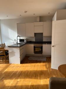 a kitchen with white cabinets and a wooden floor at Sterling Lodge Hotel in Eastbourne
