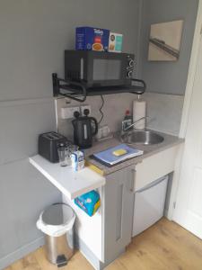 a small kitchen with a sink and a microwave at The Bolt Hole in Barmouth +2 photos