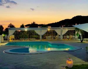 a swimming pool in front of a building with a sunset at PEPEROSA Rooms and Events - Peaceful countryside escape with pool, private parking, just minutes from the sea, Anzio and Nettuno in Nettuno