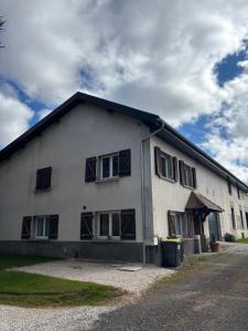 a white building with windows on the side of it at Maison chaleureuse de village - location logement entier in Lanans