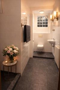 a bathroom with a toilet and a sink and a vase of flowers at City Living Trelleborg in Trelleborg