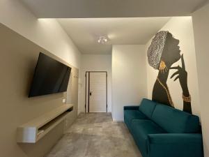 a living room with a blue couch and a tv at Appartamento Ideal con piscine e animazione Hotel Alba d Oro estate in Gatteo a Mare