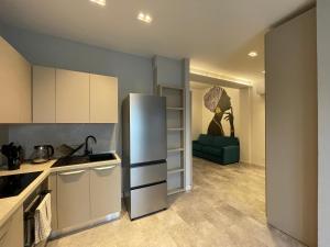 a kitchen with a refrigerator and a green couch at Appartamento Ideal con piscine e animazione Hotel Alba d Oro estate in Gatteo a Mare