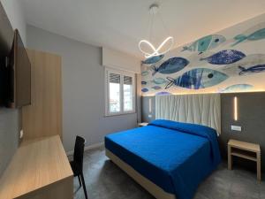 a bedroom with a blue bed with a painting on the wall at Appartamento Ideal con piscine e animazione Hotel Alba d Oro estate in Gatteo a Mare
