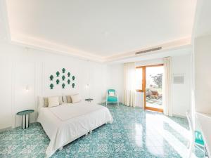 a white bedroom with a white bed and a window at Amira Capri in Anacapri