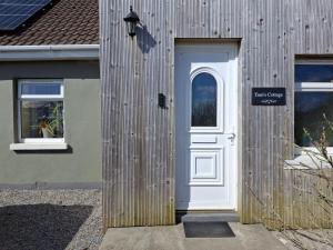 a white door on the side of a building at Tom's Alpaca Cottage in Mooncoin