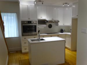a kitchen with white cabinets and a sink at villa du vignoble in Dunham