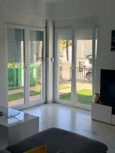 a living room with three french doors with a television at Veloura in Ulcinj