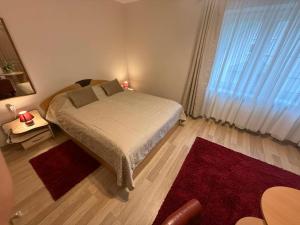 a bedroom with a bed and a window with red rugs at Ramybes sala in Palanga
