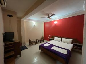 a bedroom with a bed and a red wall at Hotel Golden Palace in Chhatarpur