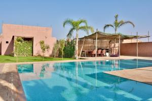 a swimming pool in front of a house with palm trees at Dar Sofia Villa in Marrakesh