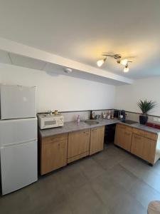 a kitchen with a white refrigerator and wooden cabinets at La Parenthèse coté Saar in Wittring