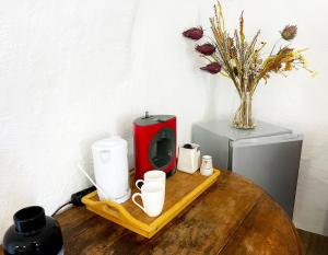 a table with a red coffee maker and a vase with flowers at Le petit refuge in Allos