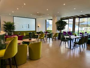a restaurant with tables and chairs and a screen at Lake & More Suite Hotel in Paratico