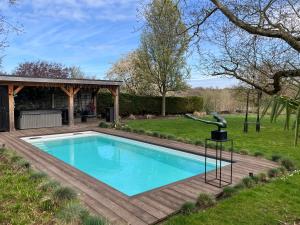 a swimming pool in a yard with a wooden deck at Rue Haute by M&M 4 sterren bed en breakfast vlakbij Maastricht in Eben-Emael