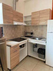 a kitchen with wooden cabinets and a white refrigerator at Corinth Beach Apartment and Hostel in Korinthos