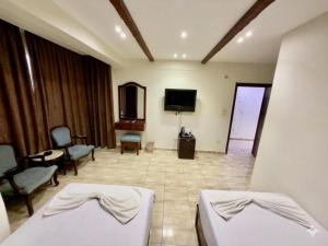 a room with two beds and a flat screen tv at Giza Pyramids Hotel in Cairo