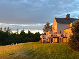 a large house on a hill with people sitting on the grass at The Lodge at Moosehead Lake in Greenville