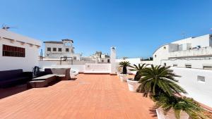 a patio with benches and palm trees on a building at TarifaMiCasa Amor de Dios in Tarifa