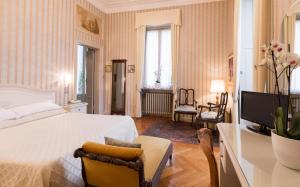 a bedroom with a bed and a television and a desk at Hotel Du Parc in Stresa