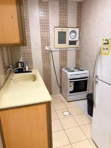 a kitchen with a sink and a microwave and a refrigerator at واحة الاحساء للشقق المخدومة in Al Hofuf