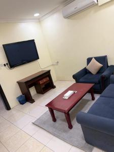 a living room with a couch and a table and a tv at واحة الاحساء للشقق المخدومة in Al Hofuf
