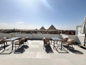 a patio with tables and chairs on a roof with pyramids at pyramids shadow inn hotel in Cairo