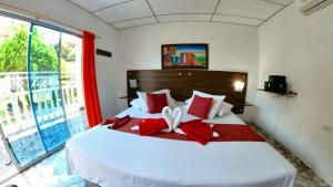 a bedroom with a large white bed with red pillows at Hotel terranova in Melgar