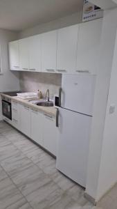 a white kitchen with white cabinets and a sink at Quiet apartment in Hadžići