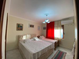 a bedroom with two beds and a red curtain at Kruja Apartment SA in Krujë