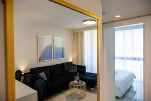 a living room with a black couch and a bed at Liz suite in Caesarea +107 photos