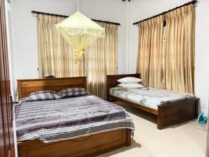 a bedroom with two beds and a chandelier at Arora Villa in Digana