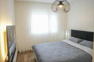 a bedroom with a bed and a television and a chandelier at StarLux Residence - Because you deserve it! in Ćuprija