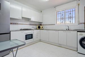 a white kitchen with white cabinets and a window at Hauzify I Casa Arboç in Platja d'Aro