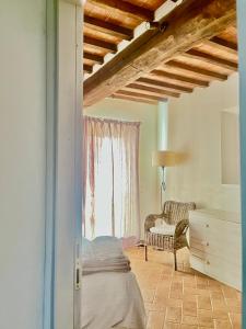 a bedroom with a bed and a chair and a window at Angolo,di Chianti in Castelnuovo Berardenga