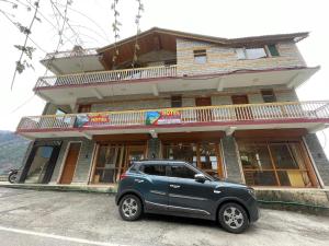 a small car parked in front of a building at Hotel sno cottage in Vashisht