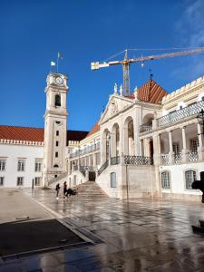 a large building with a clock tower and a crane at Green View Studios Coimbra in Coimbra