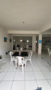 a room with a table and white chairs and a kitchen at Hotel R Soares 2 in Carutapera